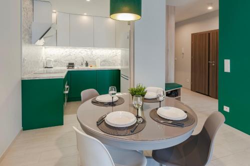 a dining room with a table and chairs and green cabinets at VacationClub - Let’s Sea Baltic Park B42 in Gąski