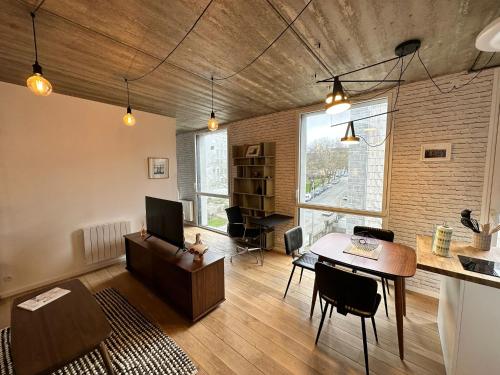 LEs Écrins de St Louis في بريست: غرفة معيشة مع طاولة وأريكة ومكتب