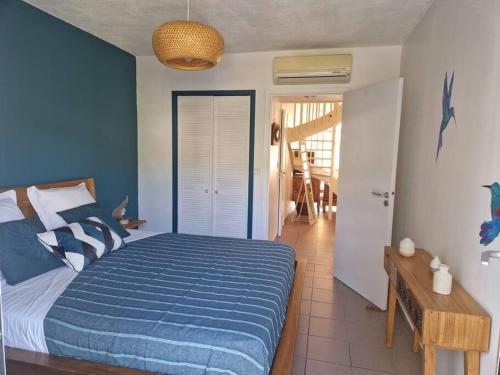 a bedroom with a bed with a blue comforter at Joli Duplex 6 pers. avec piscine in Le Diamant