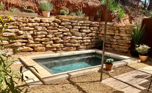 a swimming pool in front of a stone wall at Mas du Clos , Tilleul in Roussillon