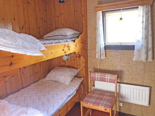 two bunk beds in a room with a chair and a window at Tänndalens Stugby in Tänndalen