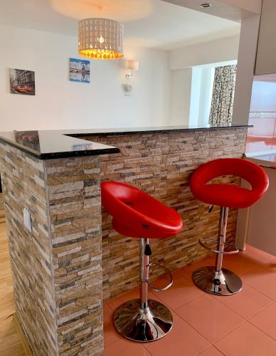 a kitchen with two red stools in front of a counter at Sunny Central Apartments Suceava in Suceava