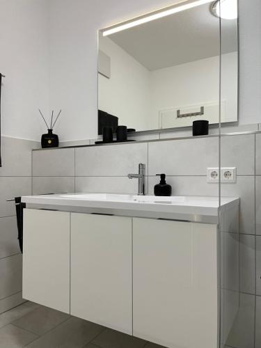 a white bathroom with a sink and a mirror at Zollernalbdomizil FeWo1 in Balingen