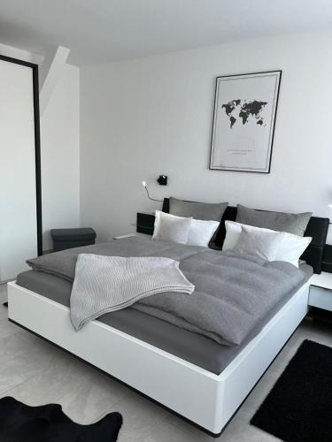 a white bedroom with a large bed with gray sheets at Zollernalbdomizil FeWo1 in Balingen