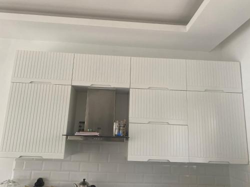 una cucina con armadietti bianchi e specchio di Konforlu,keyifli. a Emin Sitesi