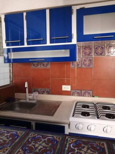 墨西哥城的住宿－El departamento azul，厨房配有水槽、炉灶和蓝色橱柜。