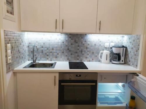 a kitchen with white cabinets and a sink at Sunset by the sea 2 in Loutraki