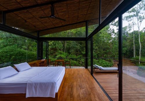 Schlafzimmer mit einem Bett auf einer Holzterrasse in der Unterkunft Kurunduketiya Private Rainforest Resort in Kalawana