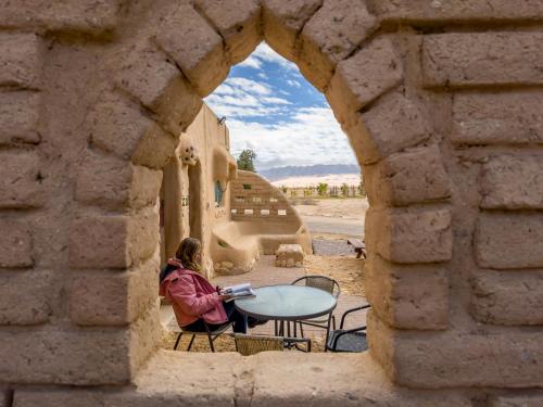 a woman sitting at a table in a stone archway at Lotan Desert Travel Hotel in Naẖal Ya‘alon