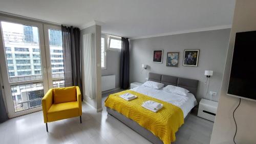 1 dormitorio con cama amarilla y silla amarilla en Elegancki apartament w sercu Warszawy, en Varsovia