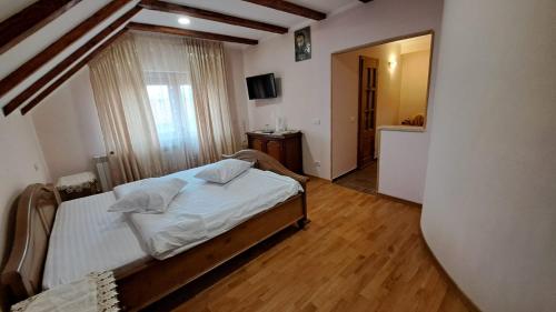 a bedroom with a bed with white sheets and a mirror at Vila Grecu in Copăcel