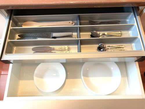 a drawer with two white bowls and utensils at Sunny Central Apartments Suceava in Suceava