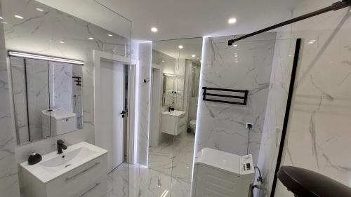 a white bathroom with a shower and a sink at Elegancki apartament w sercu Warszawy in Warsaw