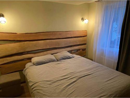 um quarto com uma cabeceira em madeira e uma cama com 2 almofadas em Sakalų sodyba 