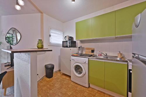 une cuisine avec des armoires vertes et une machine à laver dans l'établissement Les Comtadins - PARKING Gratuit - Balcon - Clim, à Avignon