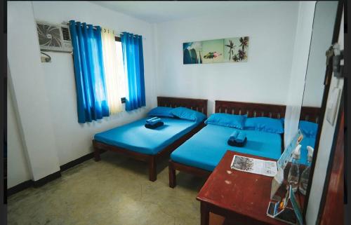 a room with two blue beds and a table at Tres Islas Hostel in General Luna
