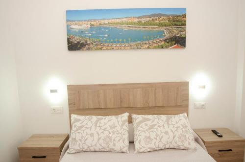Un dormitorio con una cama con una pintura encima. en Casa del Patio Andaluz, en Málaga