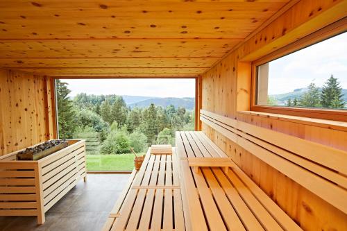 Habitación de madera con bancos y ventana grande. en Natur- & Genießerhotel Der Birkenhof en Oberstaufen