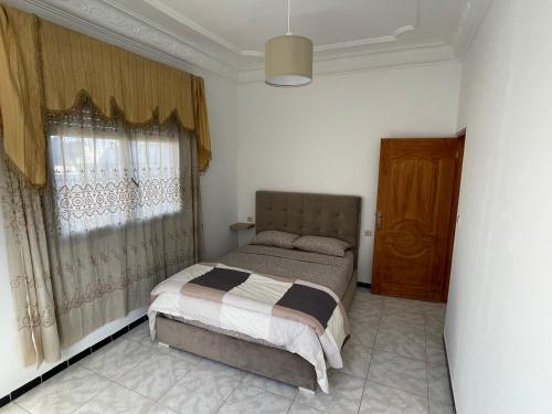 een slaapkamer met een bed en een raam met gordijnen bij Apart familiar bab okla in Tetouan