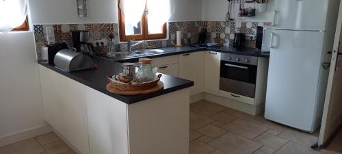 une cuisine avec un réfrigérateur blanc et un évier dans l'établissement Gîtes le clos du verger, à Maurens