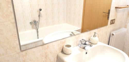 a bathroom with a sink and a mirror and a tub at Charming apartment & parking by ANTHEA HOMES in Grado