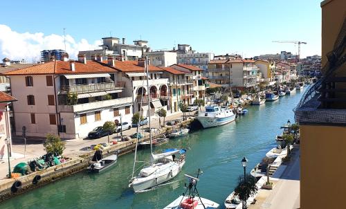 um grupo de barcos ancorados num rio com edifícios em Charming apartment & parking by ANTHEA HOMES em Grado