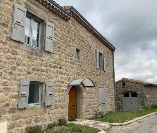 - un bâtiment en pierre avec une porte et des fenêtres en bois dans l'établissement Le Mazet, Parc Naturel Régional des Monts d'Ardèche, à Silhac