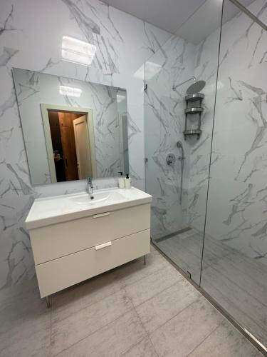 a bathroom with a sink and a shower with a mirror at Sky apartments Budova in Odesa