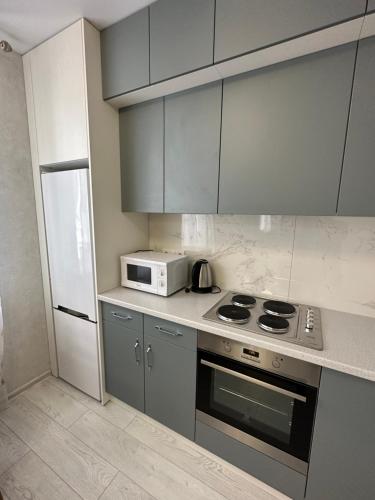 a kitchen with a stove and a microwave at Sky apartments Budova in Odesa
