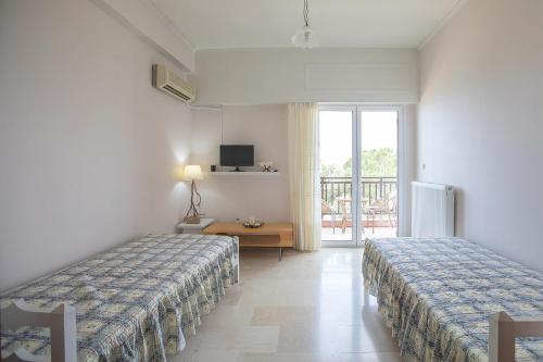 een hotelkamer met 2 bedden en een raam bij Ragia beach apartment in Póros
