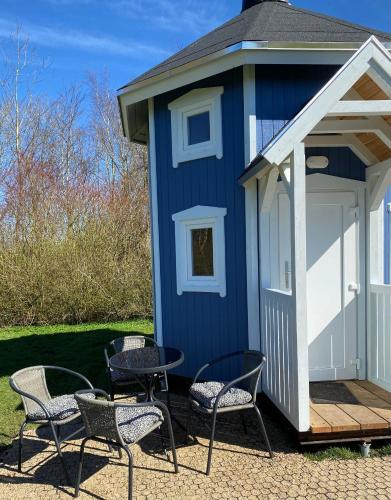 a blue shack with chairs and a table in front of it at Kroghs Tiny Houses - Hyttebyen in Grindsted