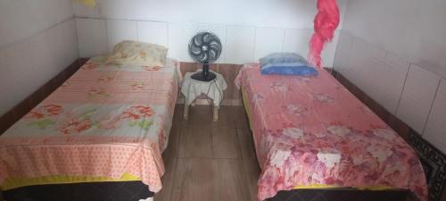 two twin beds in a small room with a fan at HOSPEDARIA pingo d ouro Cunca in Atins