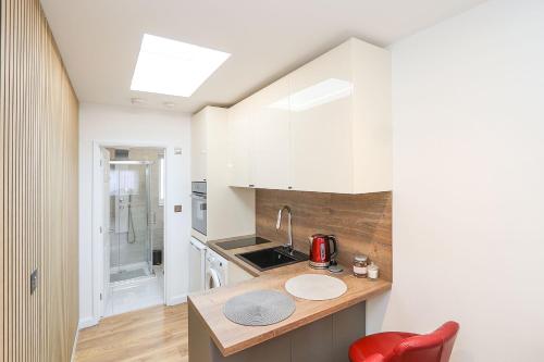 a kitchen with white cabinets and a red chair at Peaceful and Novel Place to Stay in Abbey Wood
