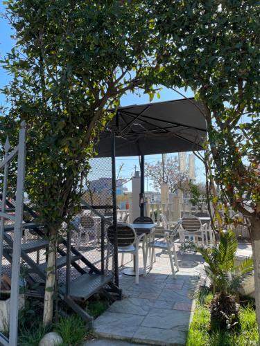 a patio with a table and chairs under an umbrella at Bajovah Apartments & Restaurant in Tirana