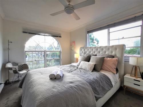 a bedroom with a large bed with a large window at Sydney Meets Miranda, Comfy 4 Bedrooms Corner House in Miranda
