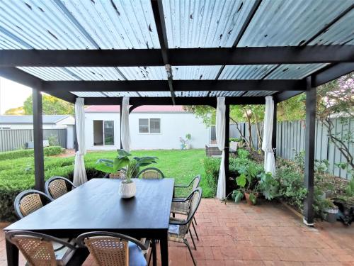 a black pergola with a table and chairs on a patio at Sydney Meets Miranda, Comfy 4 Bedrooms Corner House in Miranda