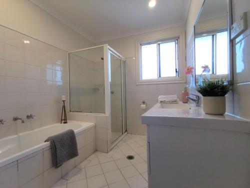 a white bathroom with a tub and a sink at Sydney Meets Miranda, Comfy 4 Bedrooms Corner House in Miranda