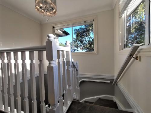 a staircase with white railings and a window at Sydney Meets Miranda, Comfy 4 Bedrooms Corner House in Miranda