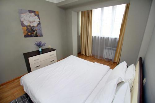 um quarto com uma cama branca e uma janela em Spacious central apartment em Almaty