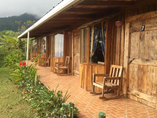 a porch of a wooden house with chairs and tables at Mirador Valle del General in La Ese