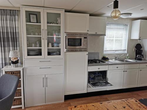 uma cozinha com armários brancos e um micro-ondas em Chalet - Dà gae nog à em Baarland