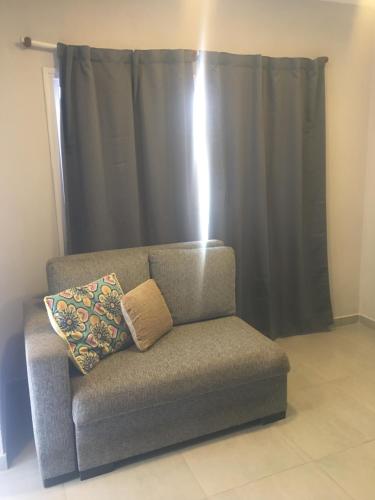 a couch with a pillow sitting in front of a curtain at Los Lirios Apart & Suite in Puerto Iguazú