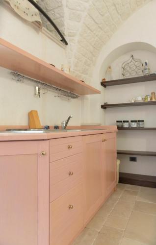 a kitchen with pink cabinets and a sink at Casetta Piazza Emanuele in Cisternino