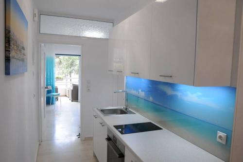 uma cozinha com armários brancos e um balcão azul em ALBATROS em Loutraki