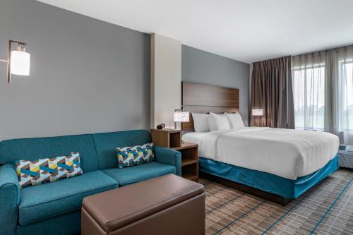 um quarto de hotel com uma cama e um sofá em MainStay Suites Waukee-West Des Moines em Waukee