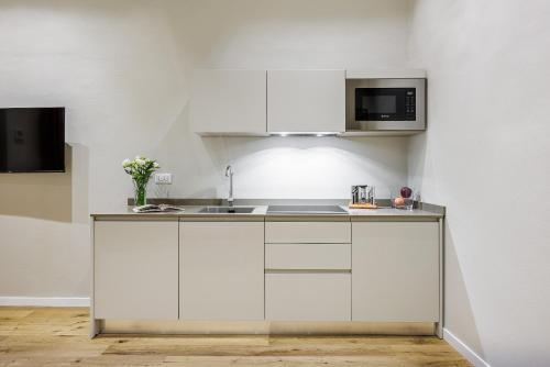 a white kitchen with a sink and a microwave at Dimora72 Luxury Rooms in Florence
