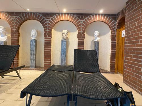 a black bench in front of a brick wall with statues at Ferienwohnung Familienglück in Sankt Englmar