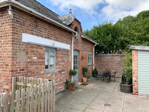 a brick house with a patio in front of it at The Little Coach House in Wales in Newtown
