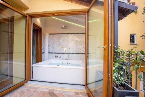 a bathroom with a tub and a glass wall at BolognaRoomscom - Falegnami Boutique in Bologna