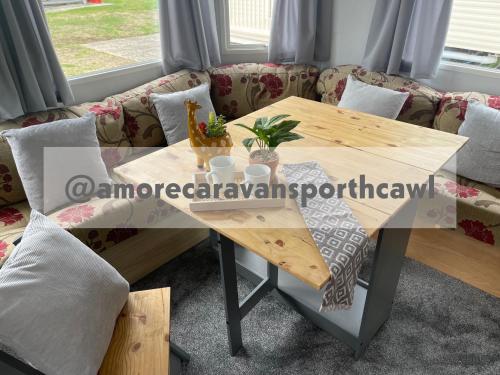 Amore Caravans في بورثكول: طاولة خشبية في غرفة معيشة مع أريكة